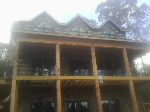 Dormers and porch framing on a large log home under construction — Roof Coating work by our crew in Stratford